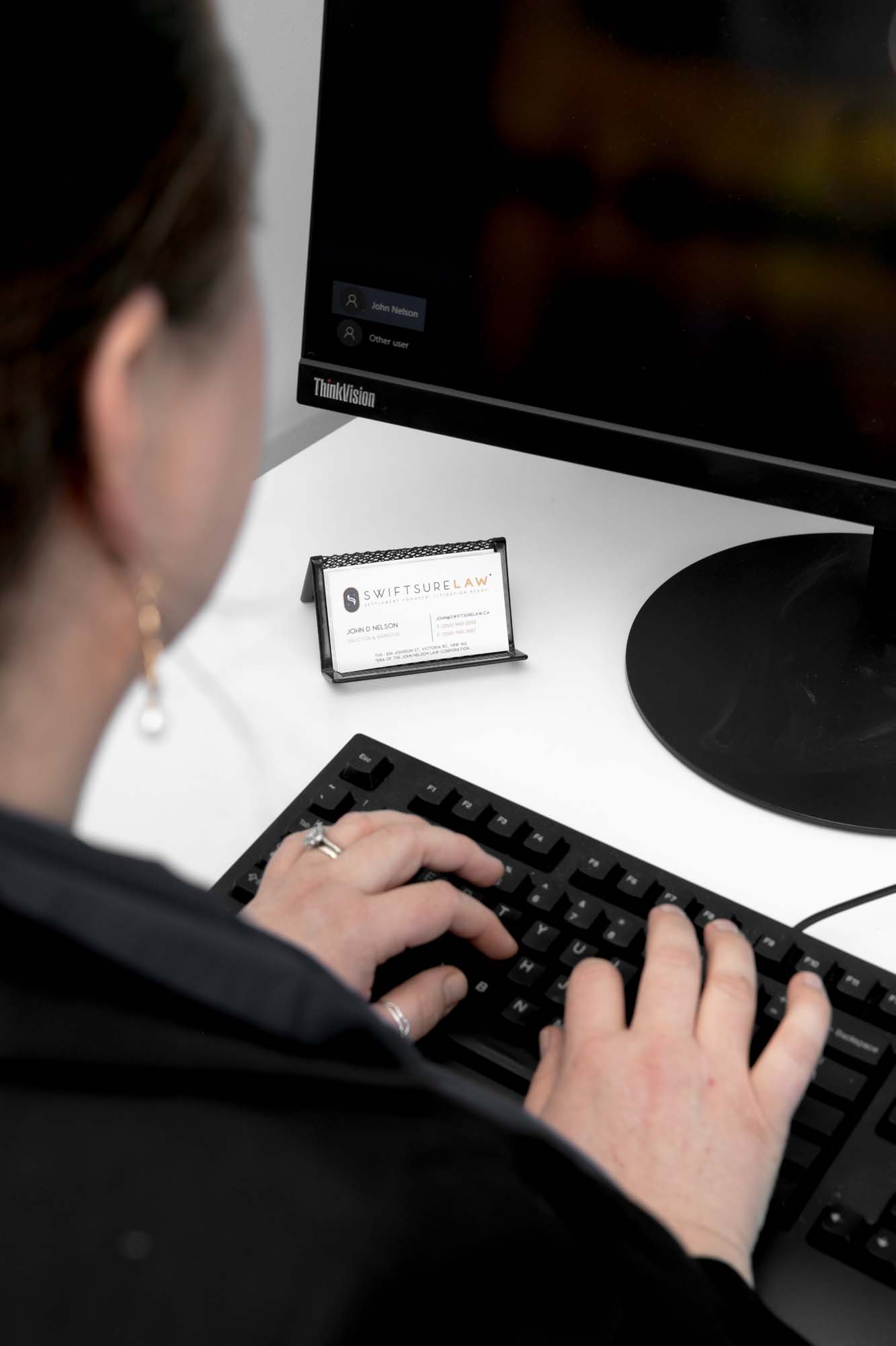 A woman typing on a keyboard and looking at a screen