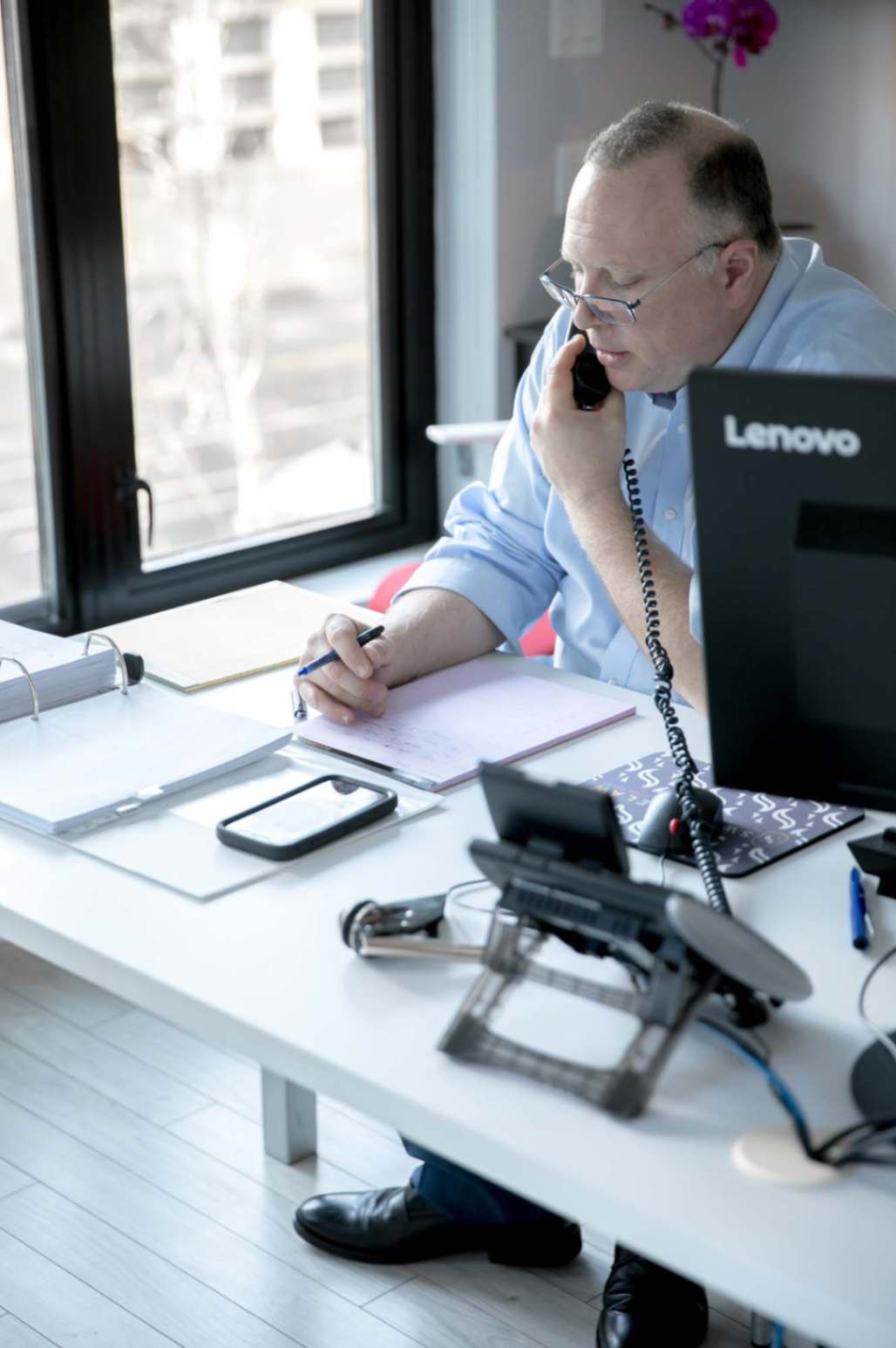 A picture of Swiftsure law founder on the phone and writing notes