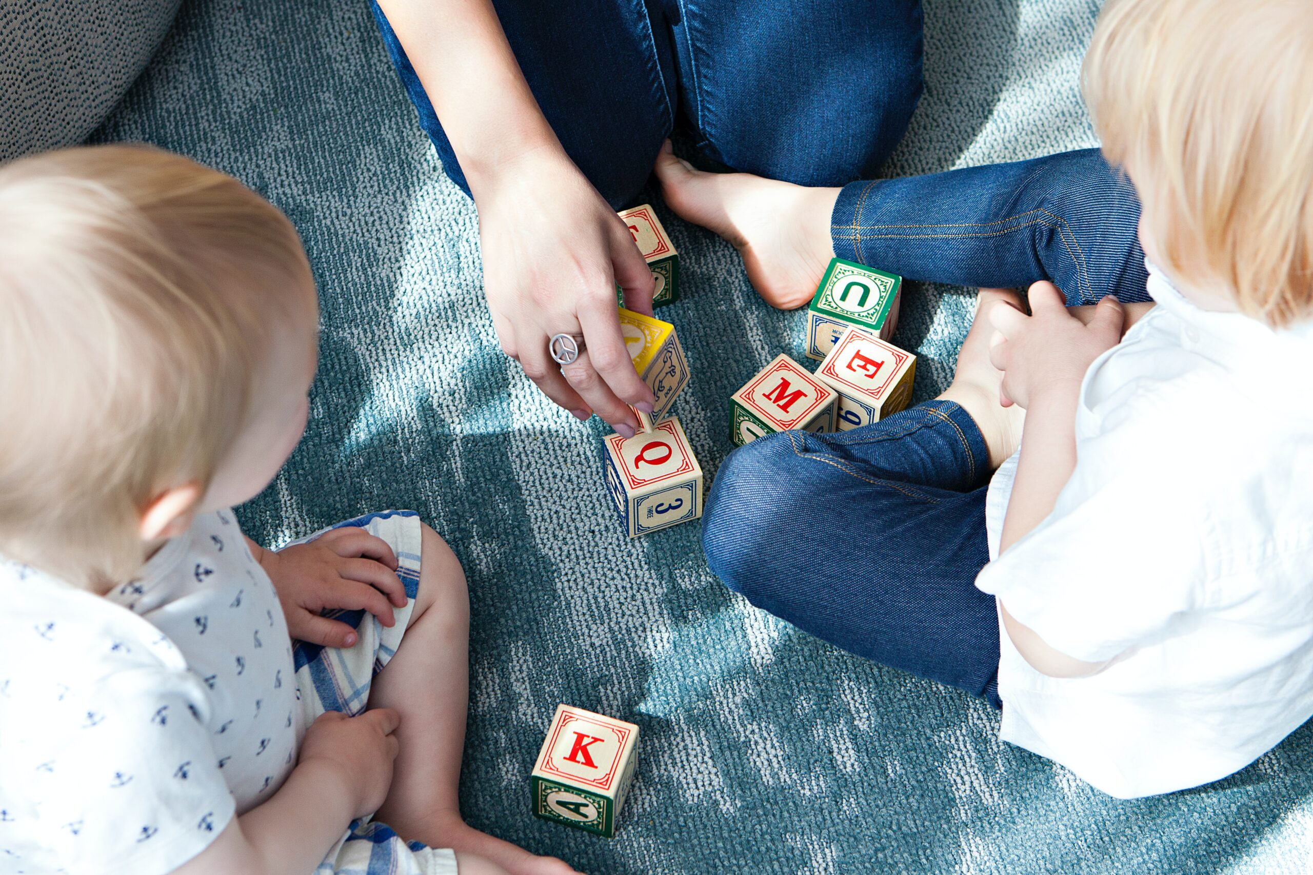 2 kids and a parent are playing with wooden blocks