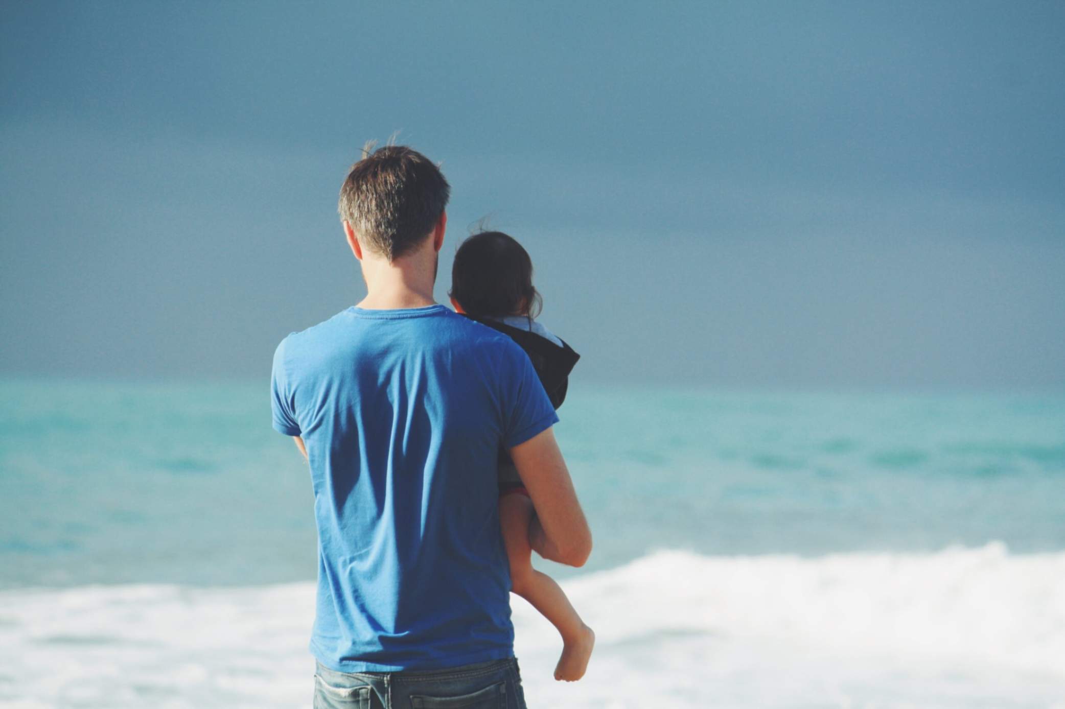 A person holding a child on the beach