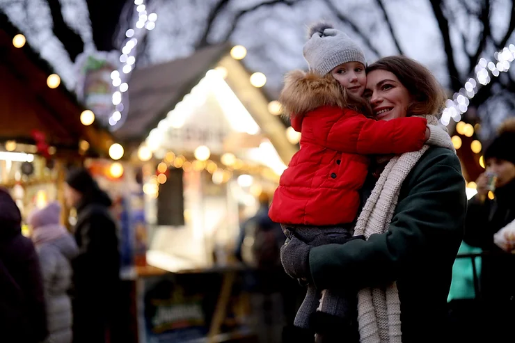 A woman holding a child surrounded by Christmas lights
