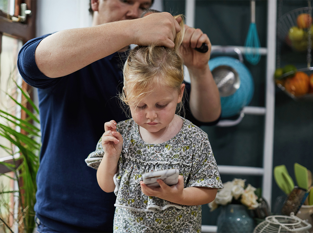 A man brusing his daughter’s hair