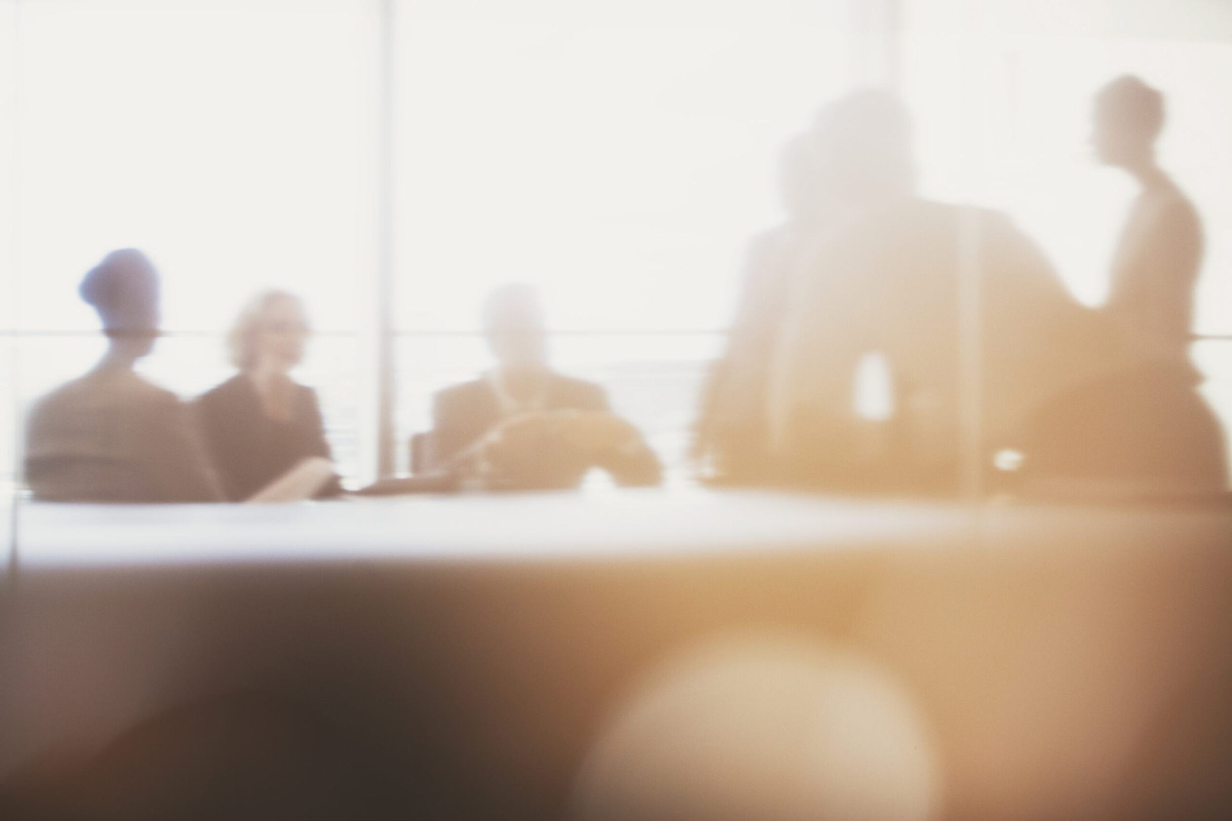 Several people sitting and standing around a board room table